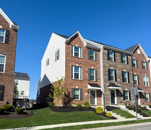 view of property with a front yard and brick siding