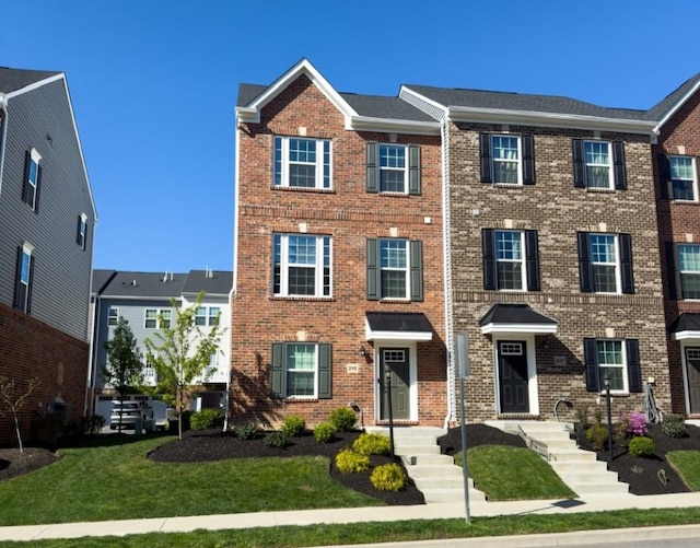view of property featuring a front yard and brick siding