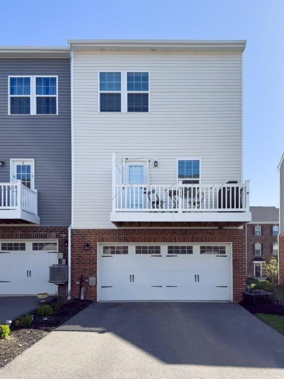 view of front of home featuring cooling unit, brick siding, a garage, and aphalt driveway