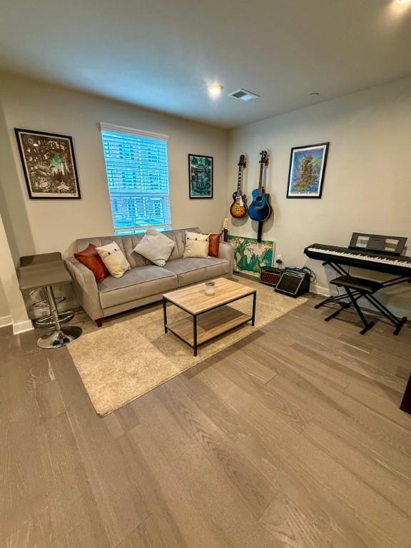 living room with wood finished floors, visible vents, and baseboards