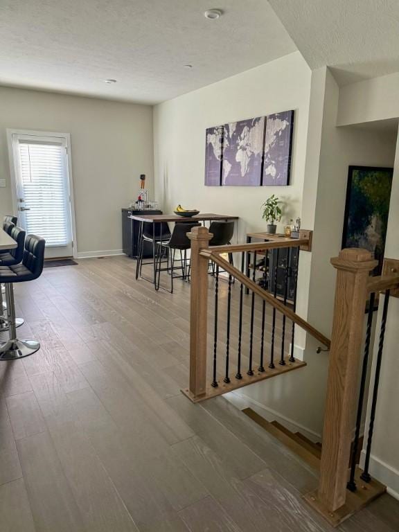 dining area featuring baseboards, wood finished floors, and a textured ceiling