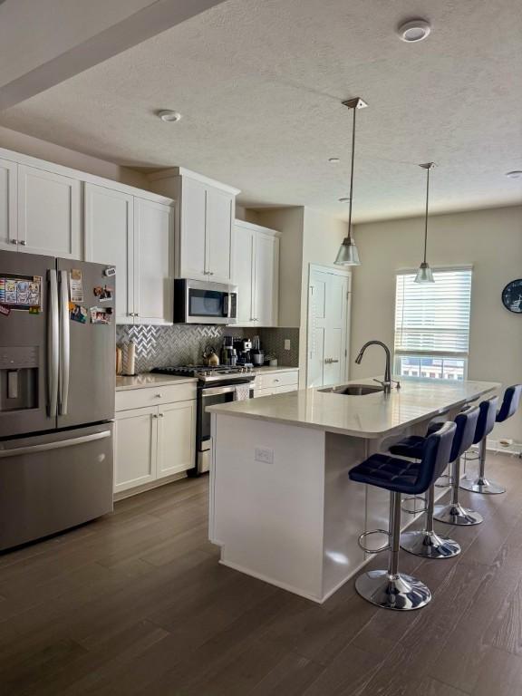 kitchen with tasteful backsplash, dark wood-style flooring, a textured ceiling, and appliances with stainless steel finishes