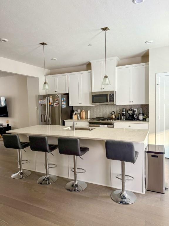 kitchen featuring white cabinets, appliances with stainless steel finishes, light wood finished floors, and a sink