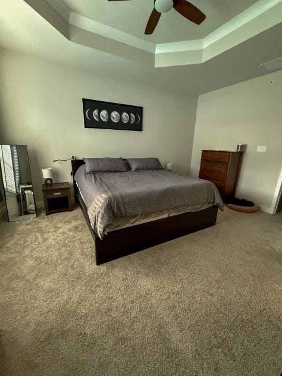 bedroom featuring ceiling fan, carpet floors, and a tray ceiling