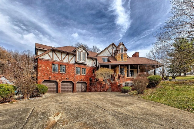 view of front of home featuring covered porch, a garage, a chimney, concrete driveway, and brick siding