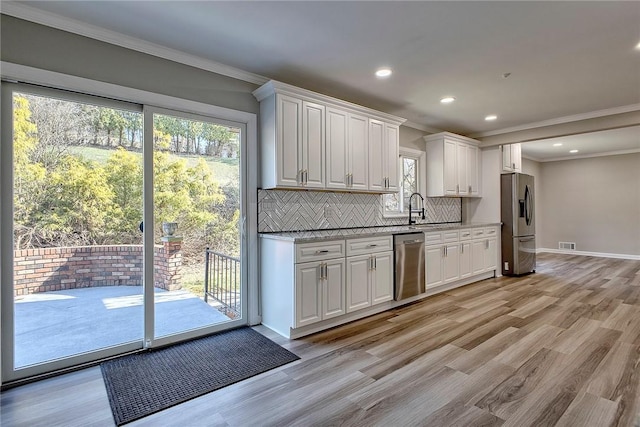 kitchen featuring visible vents, appliances with stainless steel finishes, white cabinetry, light wood finished floors, and decorative backsplash