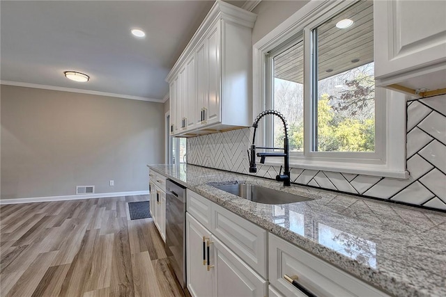 kitchen with ornamental molding, white cabinets, visible vents, dishwasher, and a sink
