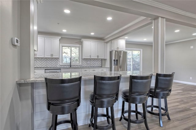 kitchen with light wood-style floors, a wealth of natural light, white cabinets, and stainless steel refrigerator with ice dispenser
