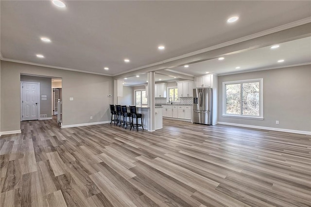 unfurnished living room with a wealth of natural light, crown molding, and wood finished floors