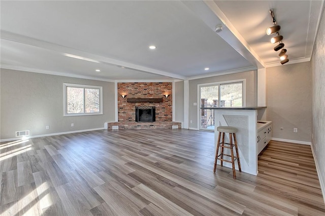 unfurnished living room with crown molding, wood finished floors, visible vents, and plenty of natural light