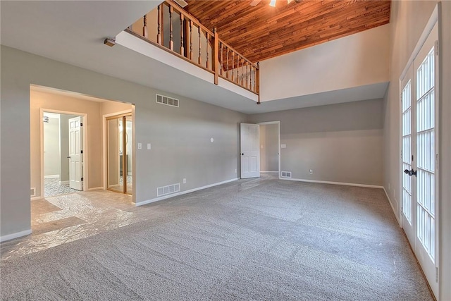 unfurnished living room with visible vents, wooden ceiling, a high ceiling, and carpet floors