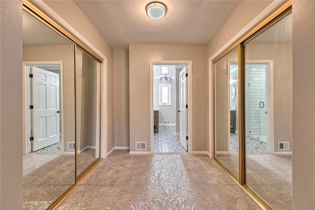 hallway with baseboards, visible vents, and carpet floors