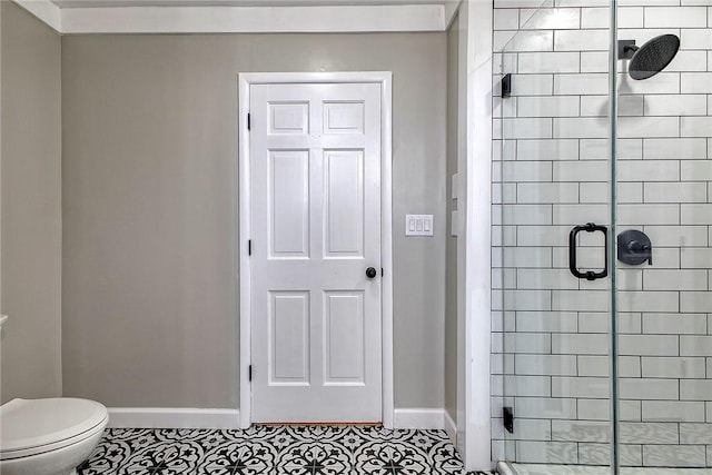 bathroom featuring toilet, baseboards, and a stall shower