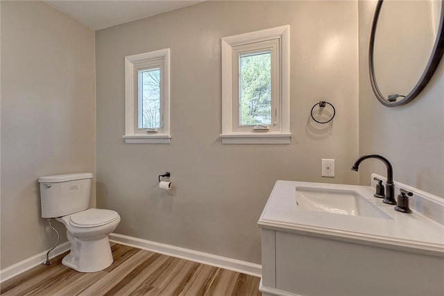 half bathroom featuring baseboards, toilet, and wood finished floors