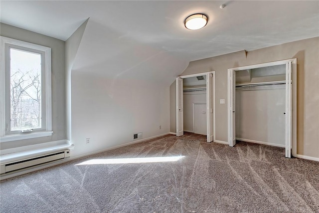 unfurnished bedroom with vaulted ceiling, visible vents, carpet flooring, multiple closets, and a baseboard radiator