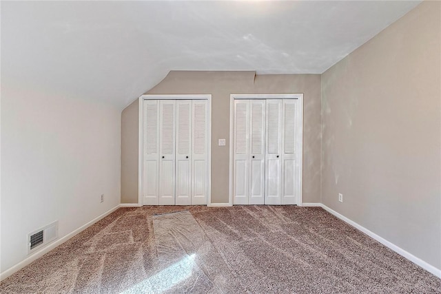 unfurnished bedroom with visible vents, multiple closets, carpet flooring, and baseboards