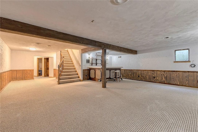 basement with carpet floors, wood walls, wainscoting, stairs, and a textured wall