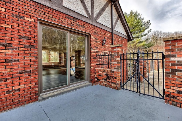 view of exterior entry with brick siding and a gate