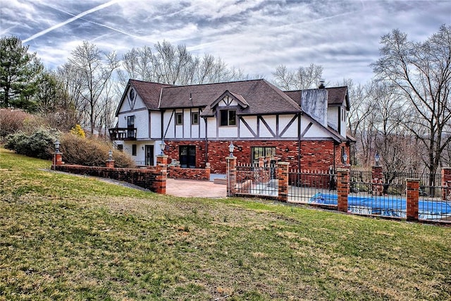 rear view of property featuring a yard, a patio area, fence, brick siding, and a fenced in pool