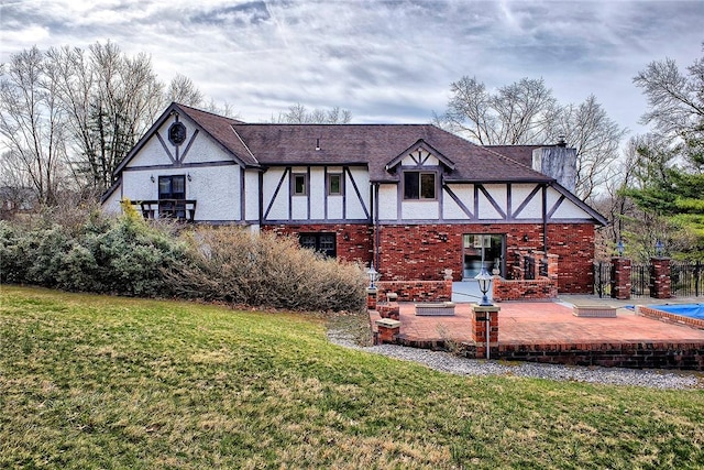 rear view of house with a patio area, brick siding, a yard, and stucco siding