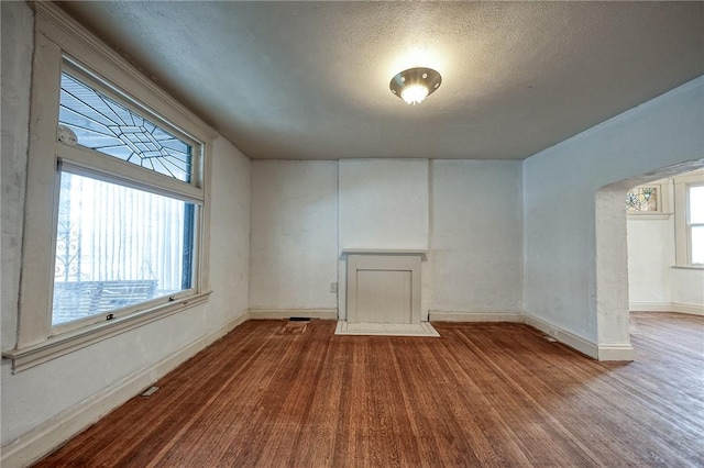 1223 Chelton Ave, Brookline, PA 15226 - unfurnished living room with arched walkways, baseboards, wood finished floors, and a textured ceiling