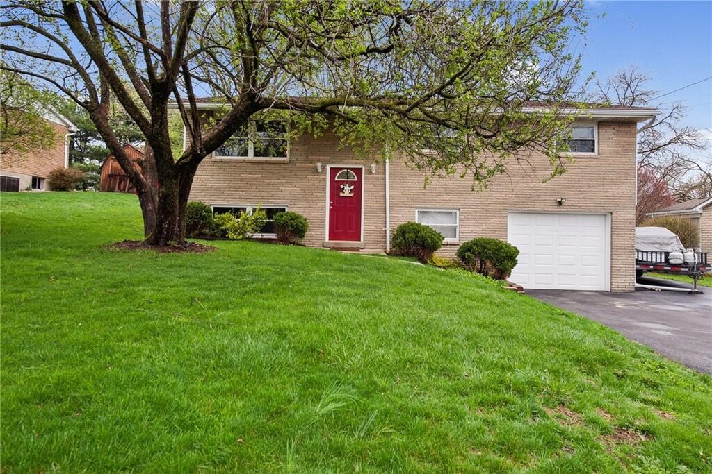 52 Nancy Dr, Penn Twp Wml, PA 15644 - bi-level home with a garage, brick siding, driveway, and a front lawn