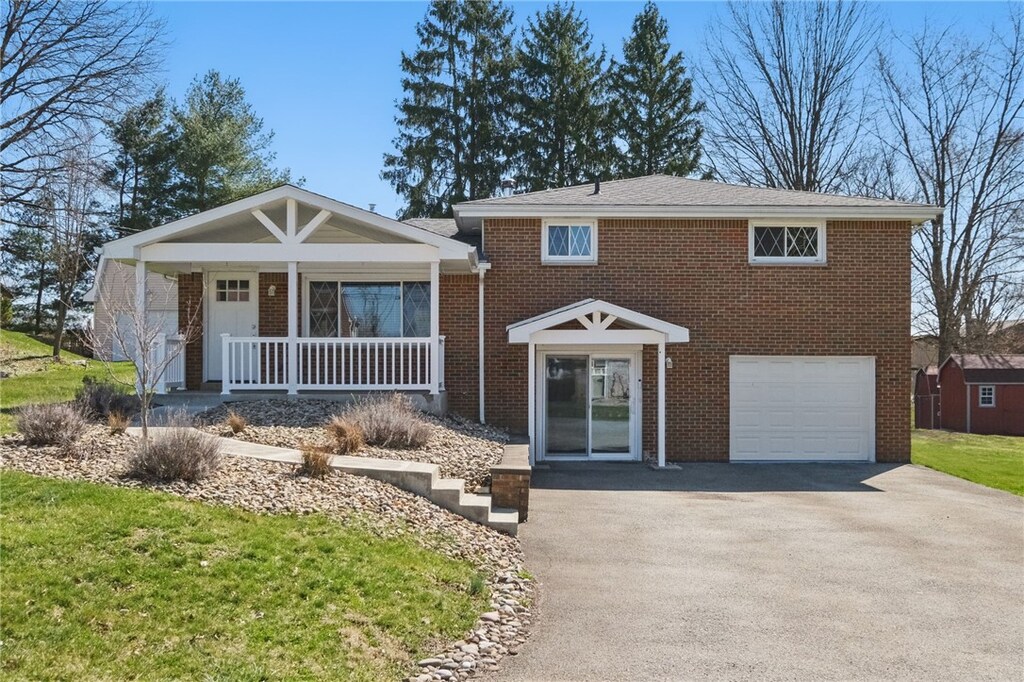 343 Rose Ave, Penn Twp Wml, PA 15636 - view of front of home featuring an attached garage, aphalt driveway, covered porch, and brick siding