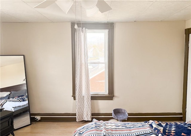 bedroom with light wood finished floors, baseboards, and a ceiling fan