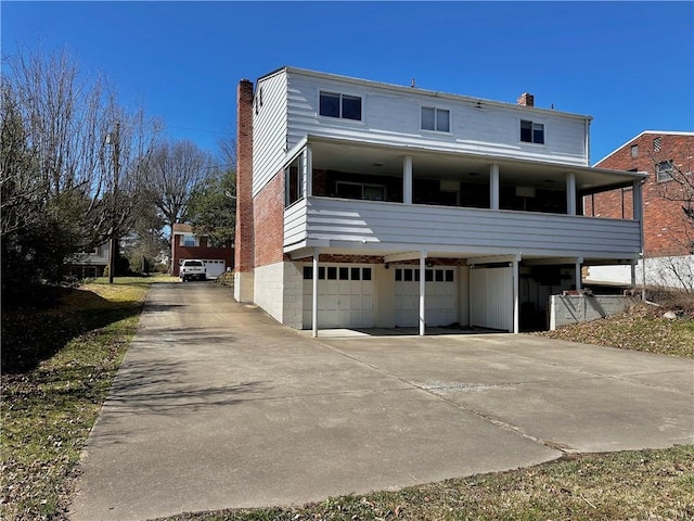 back of house with a garage, driveway, and a chimney