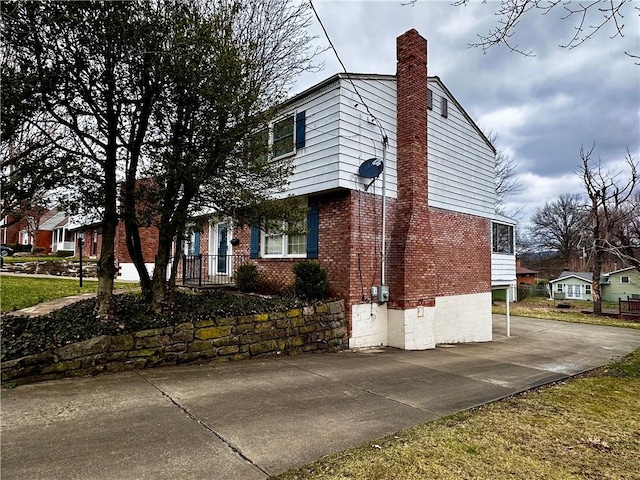 view of side of home featuring a chimney and brick siding