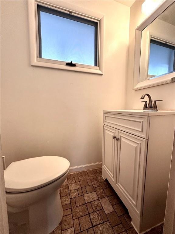 bathroom with toilet, vanity, and baseboards