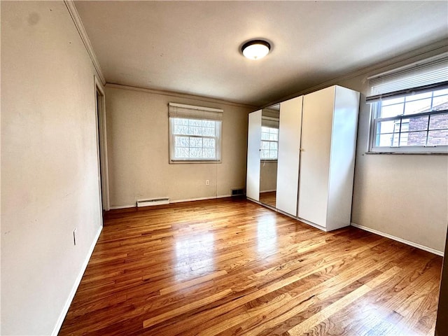 unfurnished bedroom with crown molding, multiple windows, and wood finished floors