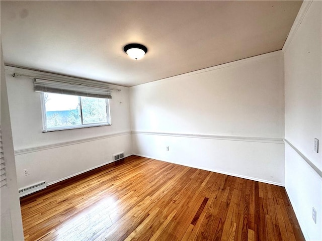 unfurnished room featuring baseboards, baseboard heating, hardwood / wood-style flooring, and visible vents