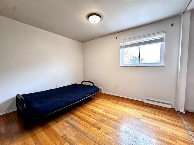 bedroom featuring visible vents, light wood-style flooring, a baseboard heating unit, and baseboards