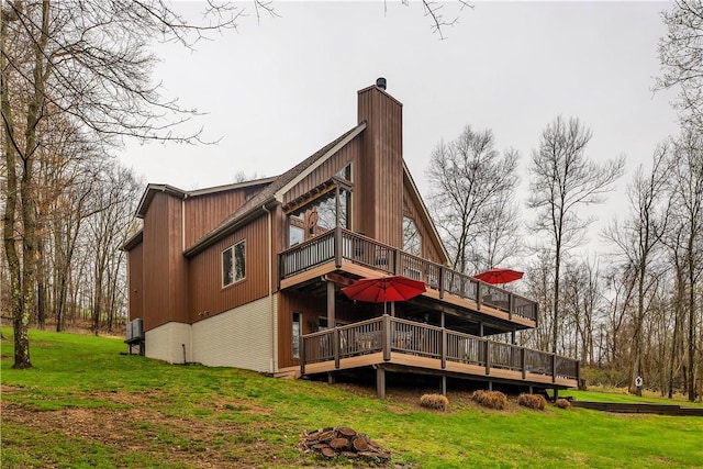 back of property featuring a chimney, a deck, and a lawn