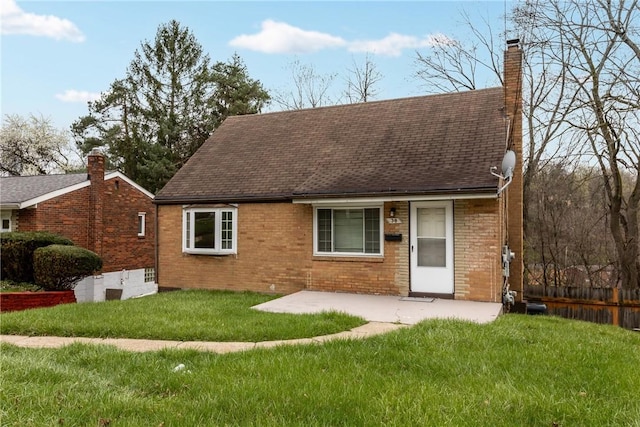 back of property with a patio, a shingled roof, a chimney, and a lawn