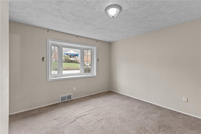 carpeted spare room featuring visible vents, a textured ceiling, and baseboards