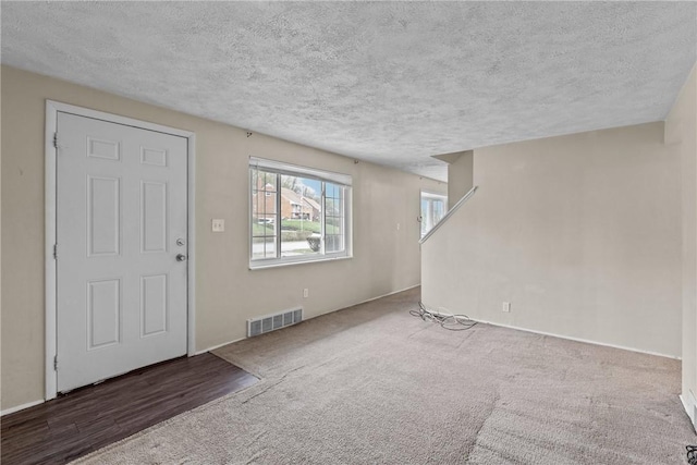 carpeted foyer entrance featuring visible vents and a textured ceiling