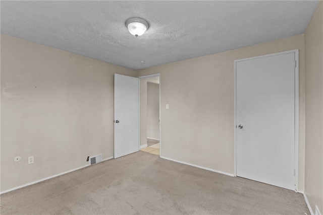 unfurnished room featuring visible vents, baseboards, carpet, and a textured ceiling