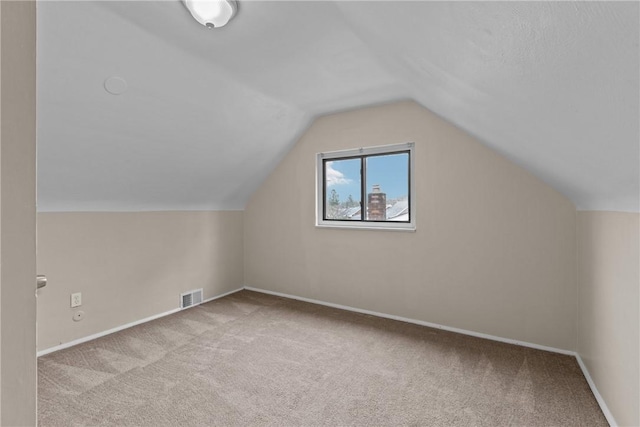 additional living space featuring carpet flooring, lofted ceiling, and visible vents