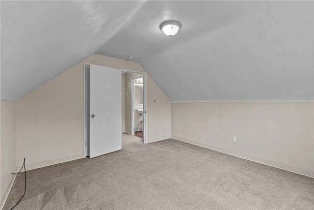 additional living space featuring baseboards, lofted ceiling, and carpet floors