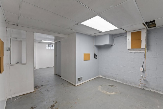 finished below grade area featuring a paneled ceiling, visible vents, and concrete block wall