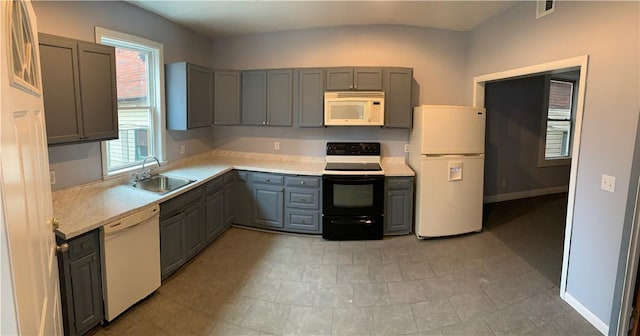 kitchen featuring visible vents, a sink, white appliances, a healthy amount of sunlight, and gray cabinets