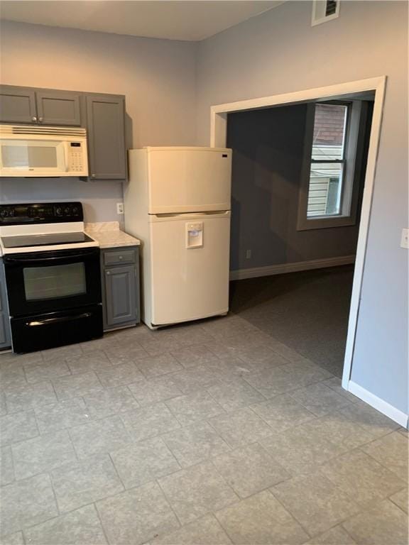 kitchen with baseboards, gray cabinetry, white appliances, and visible vents