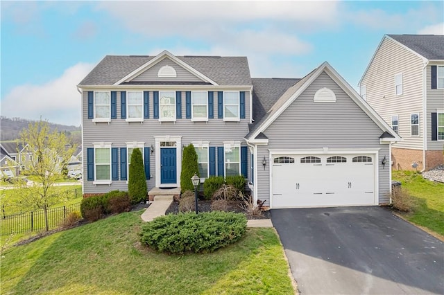 colonial house with a front yard, fence, a garage, and aphalt driveway