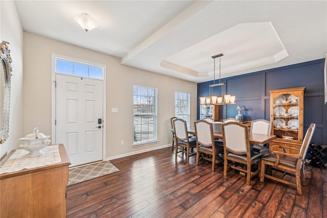 dining space with a chandelier, dark wood-style floors, a tray ceiling, and baseboards