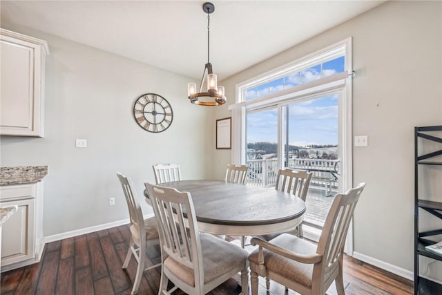 dining area featuring dark wood-type flooring, a chandelier, and baseboards