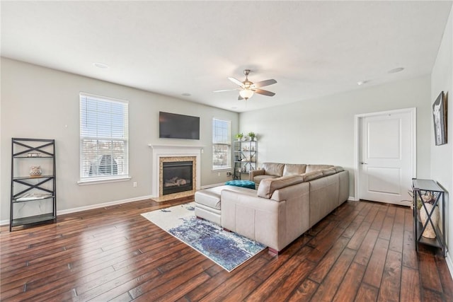 living room featuring dark wood-type flooring, ceiling fan, a fireplace, and baseboards