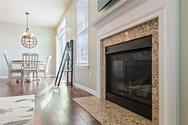 room details featuring a chandelier, a premium fireplace, wood finished floors, and baseboards