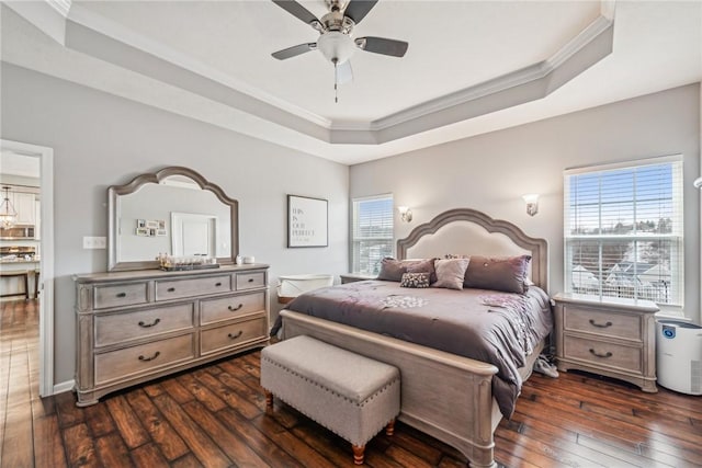 bedroom with dark wood-type flooring, a tray ceiling, ceiling fan, and ornamental molding